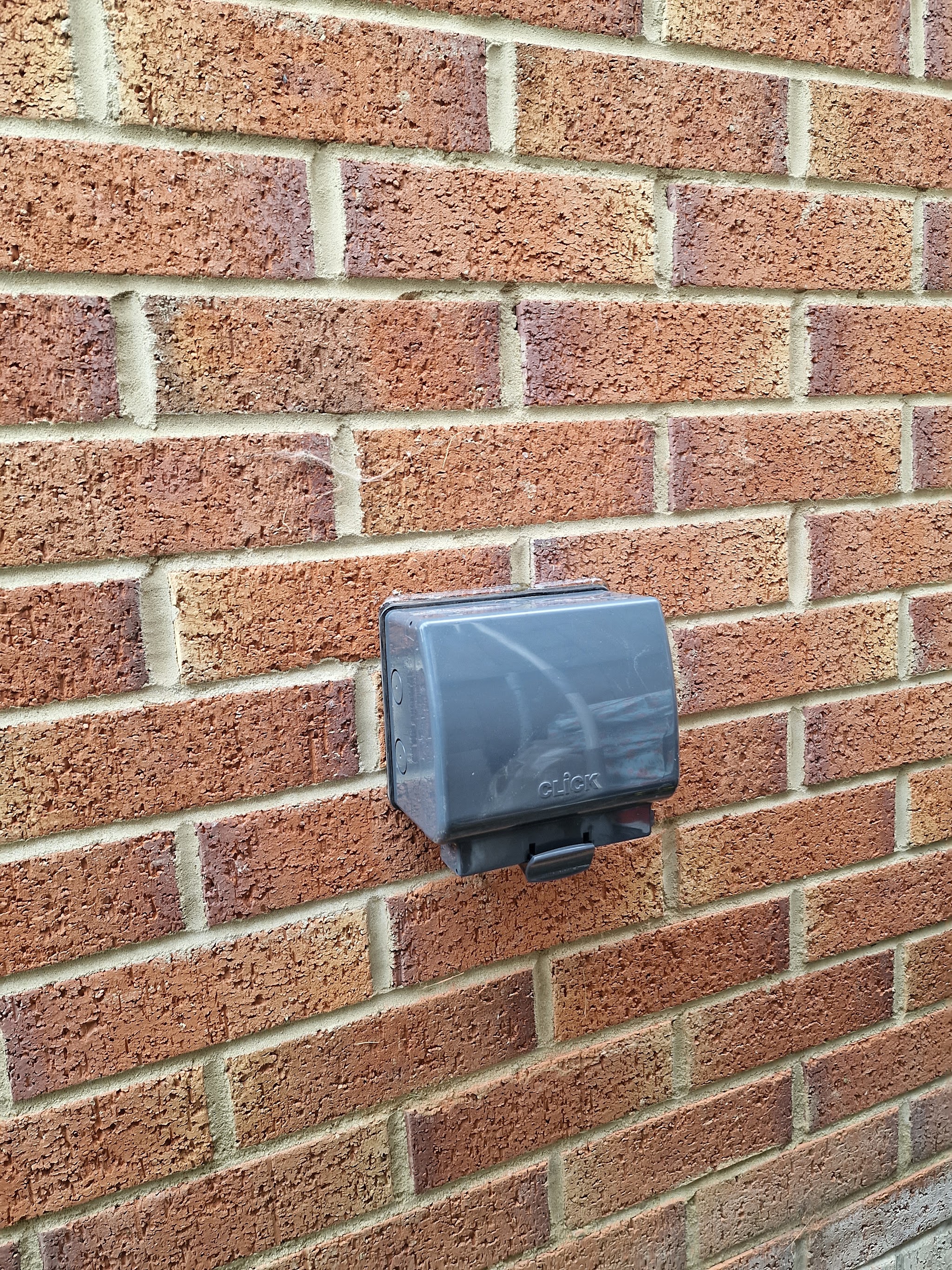 A weatherproof outdoor socket fitted on a brick wall