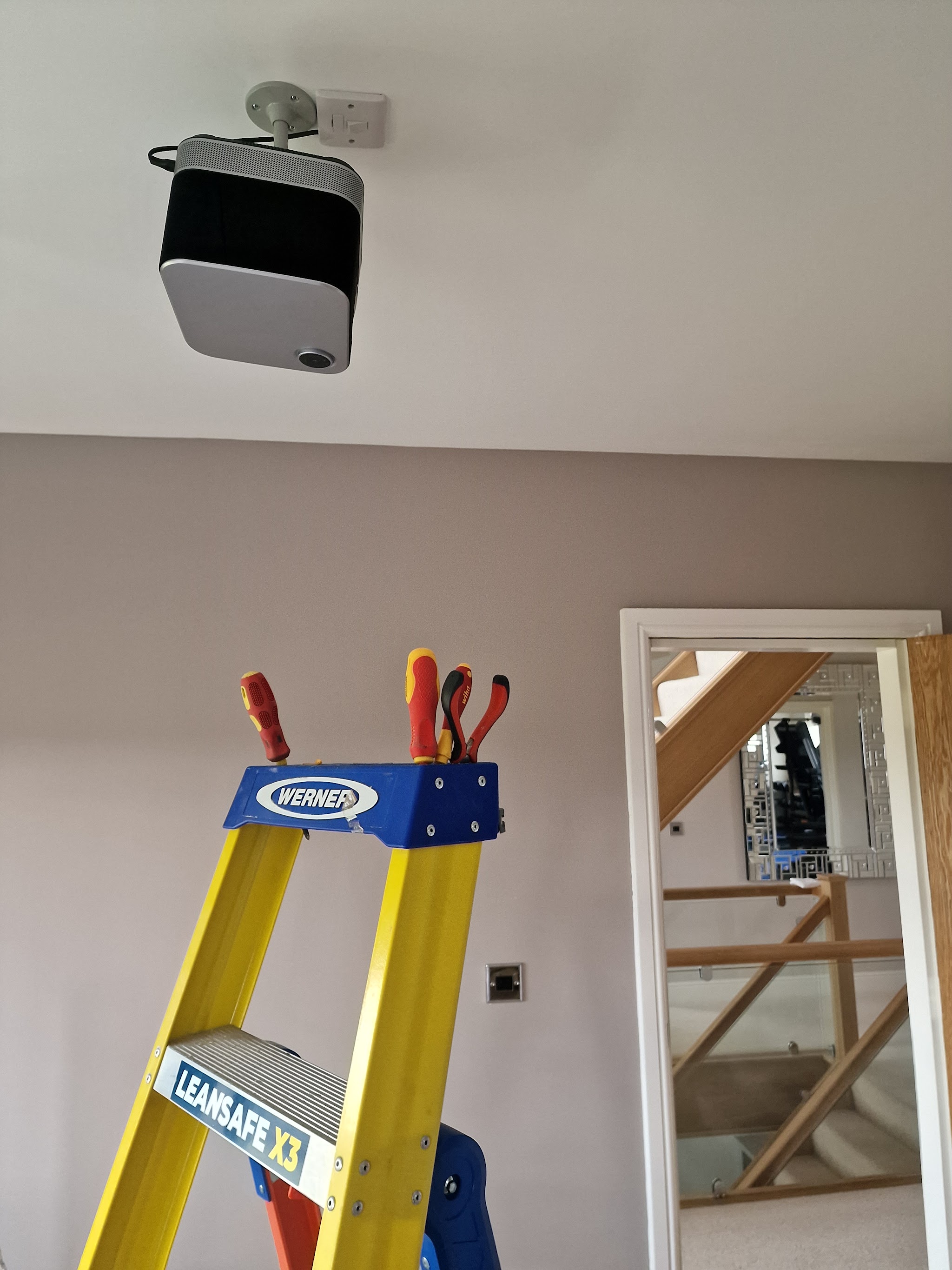A ceiling-mounted speaker with a ladder below it